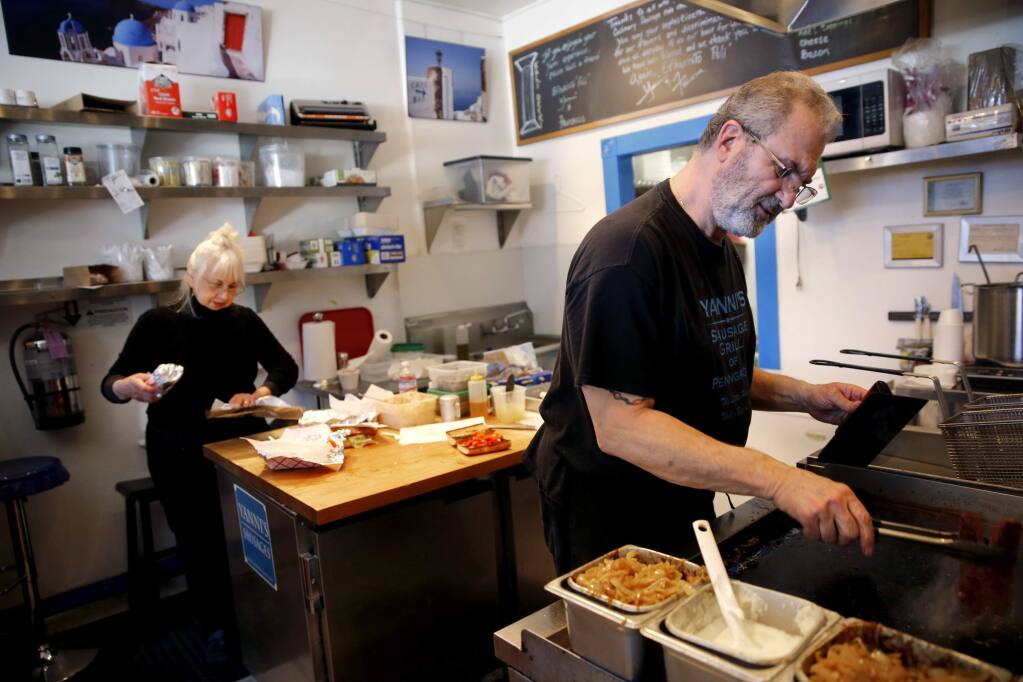John and Francesca Vrattos work to fill lunch orders during the last day of business Sunday at Yanni's Sausage Grill, Feb. 25, 2018 in Penngrove, California. (BETH SCHLANKER/The Press Democrat)