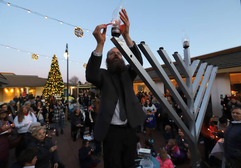 Rabbi Mendel Wolvovsky of Sonoma County Chabad Jewish Center lights the first candle of the menorah during the Montgomery Village Hanukkah Festival, Sunday, December 18, 2022, in Santa Rosa. (Darryl Bush / For The Press Democrat)