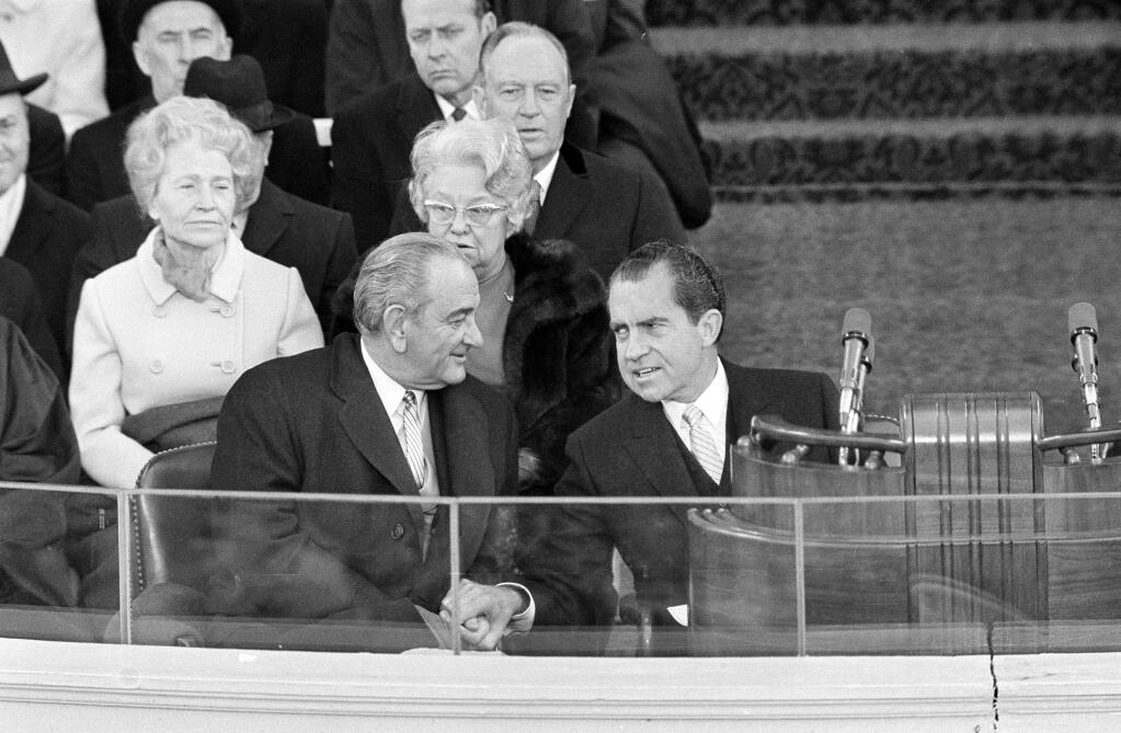 President Nixon and former President Lyndon B. Johnson clasp hands as they sit on the inaugural stand where Nixon took the Oath of Office as chief executive, in Washington, D.C., Jan. 20, 1969. (AP Photo/Preston Stroup)
