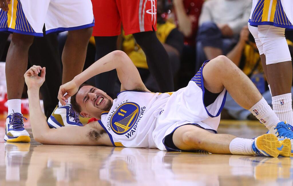 Golden State Warriors guard Klay Thompson writhes in pain after being a hard hit by the Houston Rockets during Game 5 of the Western Conference final at Oracle Arena in Oakland on Wednesday, May 27, 2015. (Christopher Chung / The Press Democrat)