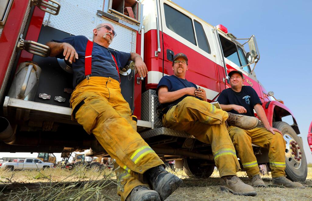 From left, Cazadero firefighters Mike Dahle, Tim Steger and Monte Rio firefighter Brian Lovett wait to confirm their 24-hour downtime after 5 days work with just short naps at the Sonoma County Fairgrounds on October 12, 2017. (photo by John Burgess/The Press Democrat)