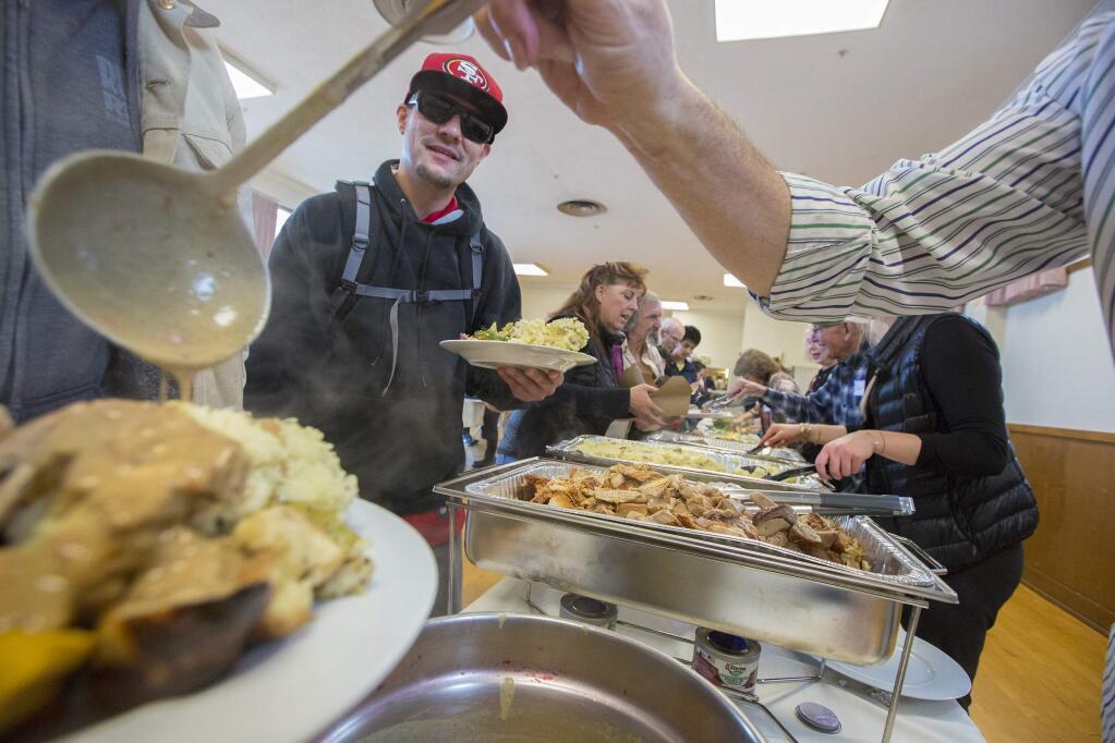 Robert Brooks, waiting for his turn, watches as Saul Gropman ladles gravy onto a guest's plate. The Sonoma Community Center gathered together [ocal businesses, service clubs, and volunteers to provide dinners for over 500 people on Thanksgiving Day, Thursday, Nov. 22, at the Sonoma Valley Veterans Memorial Hall. (Photo by Robbi Pengelly/Index-Tribune)