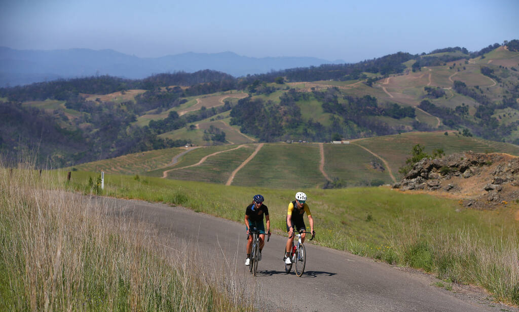 Laura and Ted King ride up Pine Flat Road near Healdsburg on Wednesday, April 21, 2021. The road is one of their favorites because of the scenery, lack of traffic and proximity to Healdsburg. Ted King was a professional cyclist in Europe for 10 years, and was a rider in the Tour de France and Giro d'Italia twice. Laura King is the race director of their gravel race Rooted Vermont and works to promote gender equality in cycling.  (Christopher Chung/ The Press Democrat)