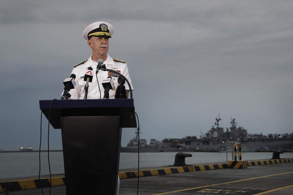 Commander of the U.S. Pacific Fleet, Scott Swift answers questions during a press conference with the USS John S. McCain and USS America docked in the background at Singapore's Changi naval base on Tuesday, Aug. 22, 2017, in Singapore. The focus of the search for 10 U.S. sailors missing after a collision between the USS John S. McCain and an oil tanker in Southeast Asian waters shifted Tuesday to the damaged destroyer's flooded compartments. (AP Photo/Wong Maye-E)
