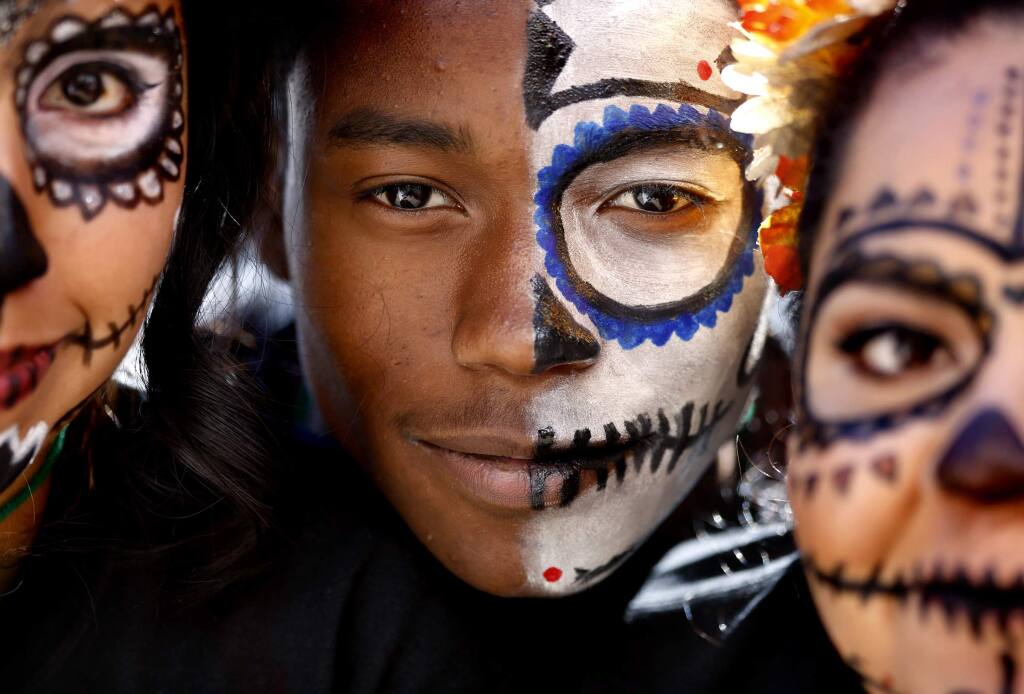 Tre'von Brown, 16, center, Lupe Lopez, 16, left, and Jess Herrera, 16, right, of the Santa Rosa HIgh School Latinos Unidos club show off their calaveras make-up during a Dia de los Muertos celebration at Old Courthouse Square in Santa Rosa, California on Sunday, November 2, 2014. (BETH SCHLANKER/ The Press Democrat)