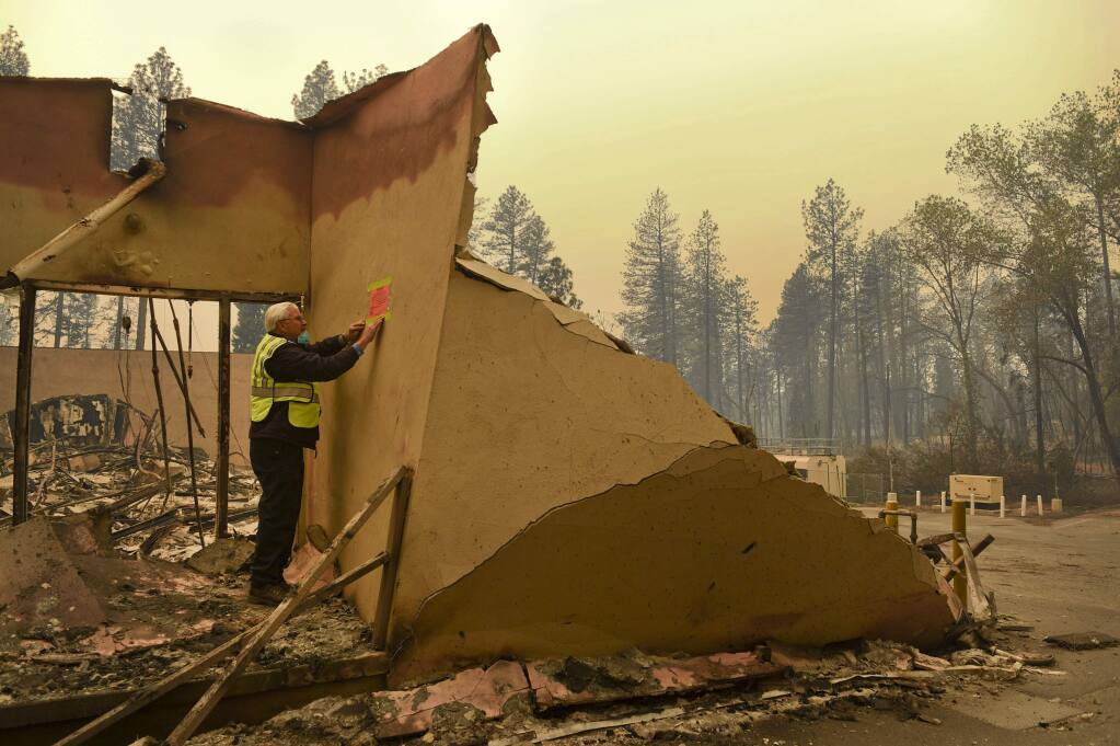 An official with the Office of Statewide Health Planning & Development marks a building damaged by wildfire, in Paradise, Calif., Monday, Nov. 12, 2018. (Hector Amezcua/The Sacramento Bee via AP)