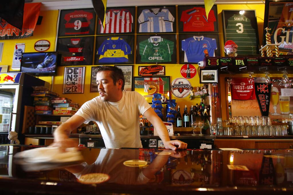 Bartender Jackson Edwards wipes down the counters at the soccer friendly Sweet Spot Pub & Lounge along 4th Street in Santa Rosa. The bar plans to open early to showcase the 2018 World Cup games being played this year in Russia. (Conner Jay/The Press Democrat) 2014