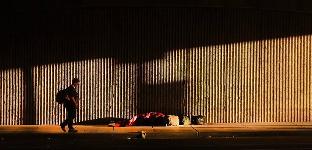 A homeless man sleeps underneath Highway 101 on Sixth Street in Santa Rosa. (KENT PORTER / Press Democrat)