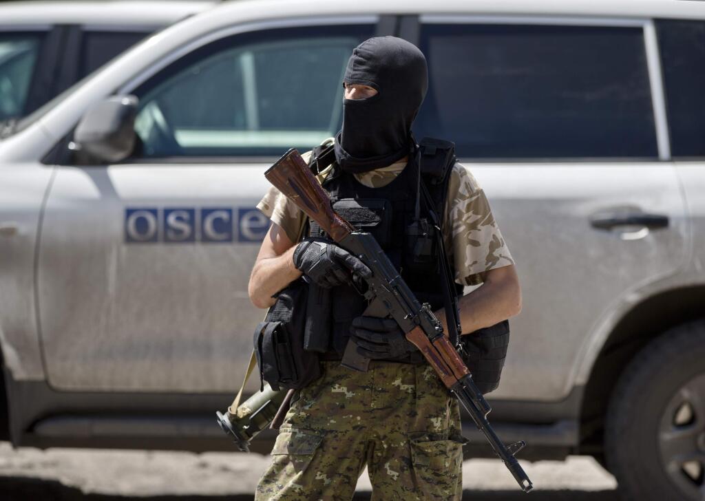 A pro-Russian rebel stands outside the railway station after members of the OSCE mission to Ukraine and Holland's National Forensic Investigations Team inspected a refrigerated train loaded with the bodies of passengers in Torez, eastern Ukraine, 15 kilometers (9 miles) from the crash site of Malaysia Airlines Flight 17, Monday, July 21, 2014. (AP Photo/Vadim Ghirda)