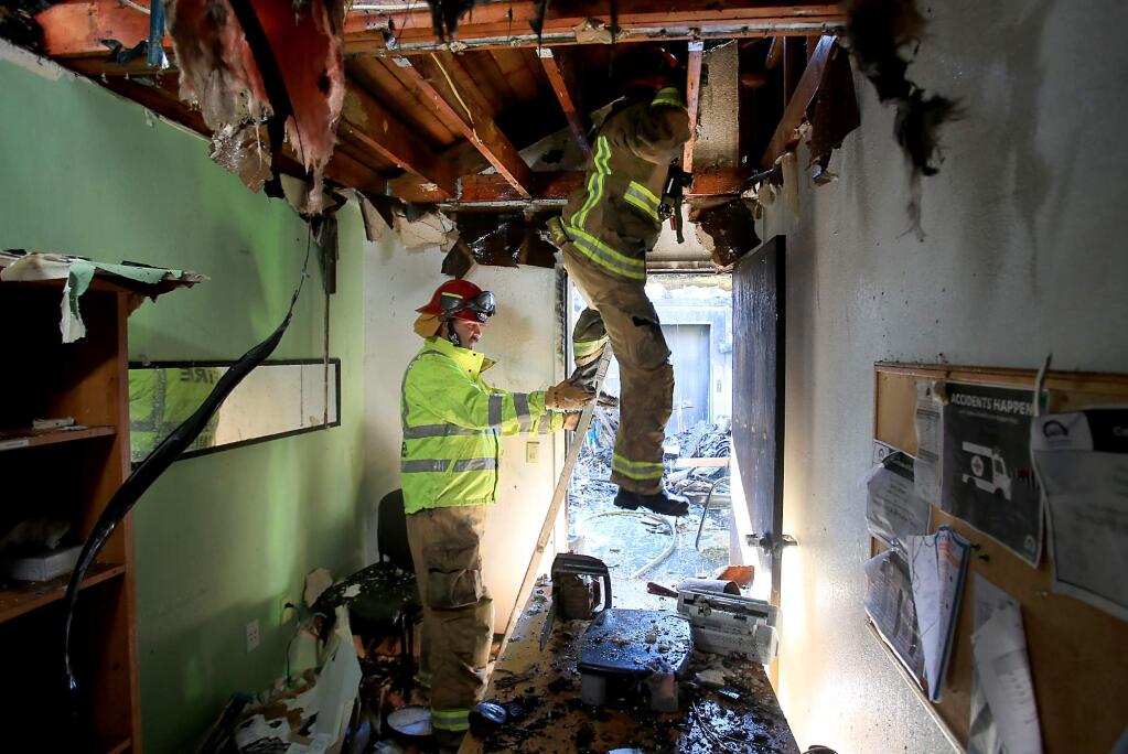 Cal Fire captain Brian Borba steps out of the Russian River Health Center attic with the help of Cal Fire captain and Camp Meeker firefighter Henry Baker , Saturday Dec. 26, 2015 in Guerneville. (Kent Porter / Press Democrat) 2015