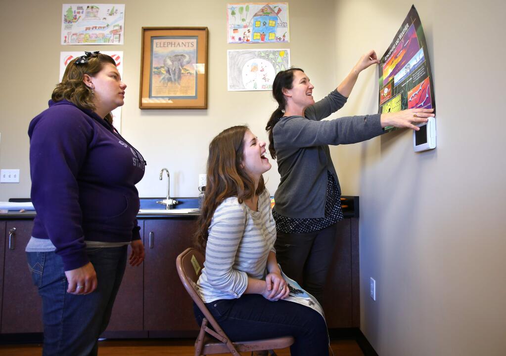 Teaching assistants Liz Perris, right, Kimberly Harris and Sarah Basham put up a poster in front of a 'redirection chair', as they set up a classroom in the new location for New Directions school, in Santa Rosa on Tuesday, November 25, 2014. (Christopher Chung/ The Press Democrat)