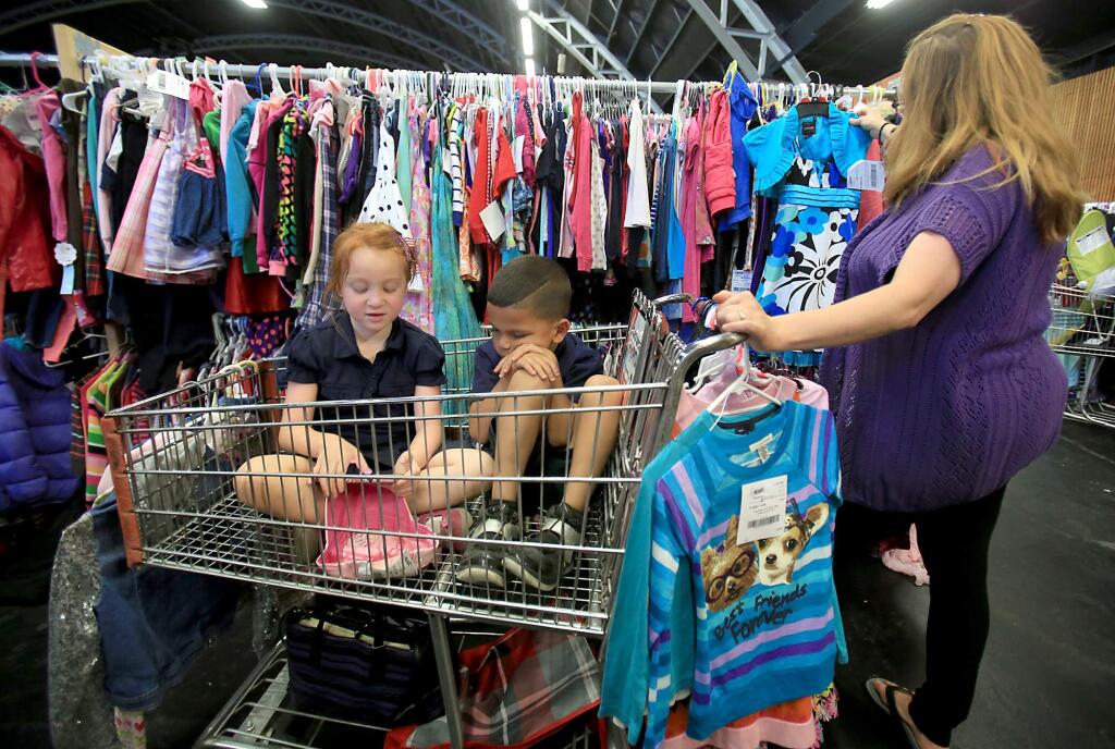 Samantha Makinano shops for clothes at the Just Between Friends sale at the Sonoma County Fairgrounds in Santa Rosa, Thursday Oct. 15, 2015 as her daughter Nayla, 7 and cousin Curtis Hall wait patiently. (Kent Porter / Press Democrat) 2015