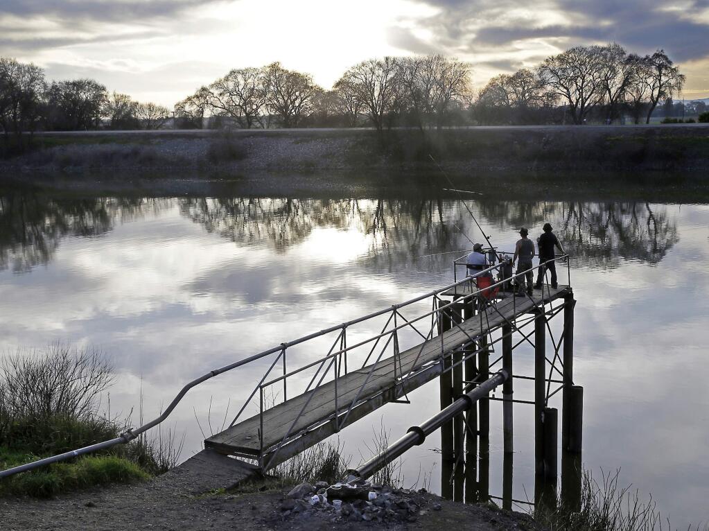 FILE - In this Feb. 23, 2016 file photo, people try to catch fish along the Sacramento River in the San Joaquin-Sacramento River Delta, near Courtland, Calif. (AP Photo/Rich Pedroncelli, File)