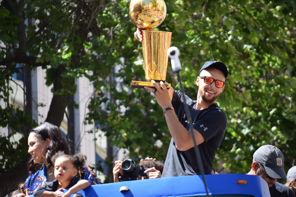 Warriors' Stephen Curry shows off the NBA championship trophy during the team's victory parade through Oakland on Thursday, June 15, 2017. (PAUL GULLIXSON/ PD)