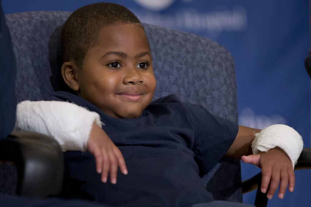 Double-hand transplant recipient eight-year-old Zion Harvey smiles during a news conference Tuesday, July 28, 2015, at The Childrens Hospital of Philadelphia (CHOP) in Philadelphia. Surgeons said Harvey of Baltimore who lost his limbs to a serious infection, has become the youngest patient to receive a double-hand transplant. (AP Photo/Matt Rourke)