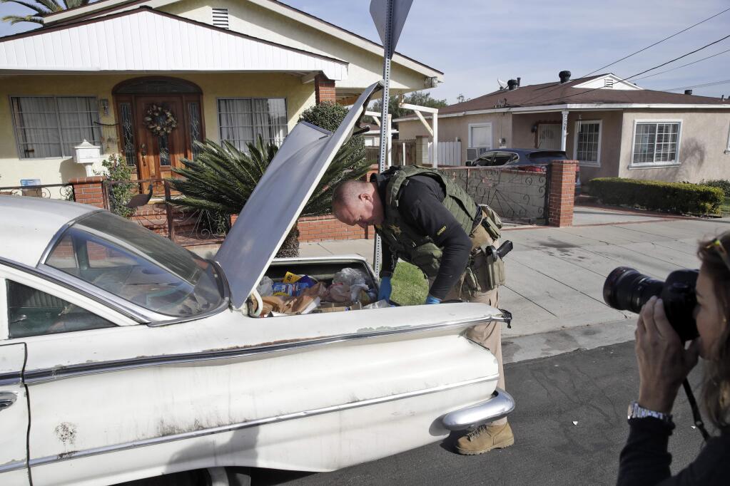 A member of the Los Angeles Sheriff's Dept. searches a vehicle during an investigation outside of a home in connection with a a cold case Wednesday, Feb. 5, 2020, in Los Angeles. Search warrants were served Wednesday at locations in California and Washington state in the investigation of the disappearance of Kristin Smart, the California Polytechnic State University, San Luis Obispo student who disappeared in 1996. (AP Photo/Marcio Jose Sanchez)