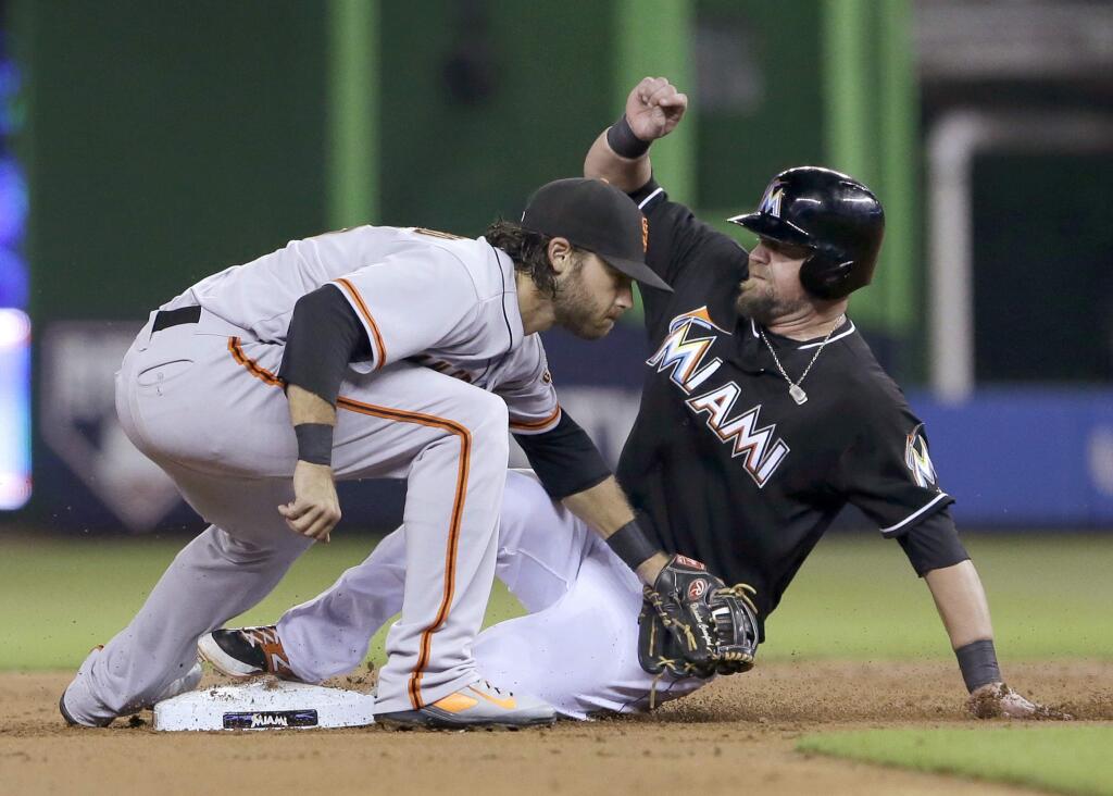Miami Marlins' Casey McGehee steals second base as San Francisco Giants shortstop Brandon Crawford is unable to tag him out in time during the first inning of a baseball game, Saturday, July 19, 2014, in Miami. (AP Photo/Wilfredo Lee)