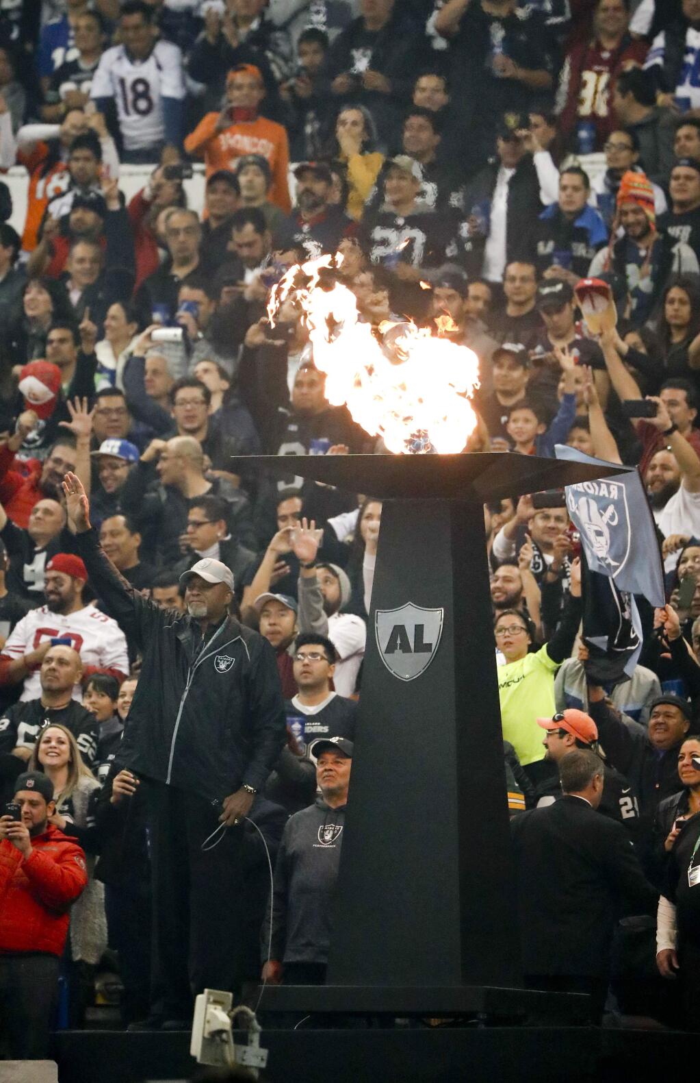 Tommie Smith, below left, lights the torch in in honor of former Oakland Raiders before an NFL football game Monday, Nov. 21, 2016, in Mexico City. Smith is famous for his 1968 Olympics protest. (AP Photo/Eduardo Verdugo)