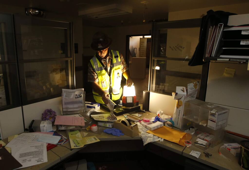 In this photo taken Thursday, Oct. 17, 2019, Joe Budds, a foreman for the Otto Construction Co., looks over a nurses' station hurriedly abandoned at the Feather River Hospital as last year's Camp Fire approached, while touring the facility in Paradise, Calif. Once the town's largest employer, Feather River Hospital still shows signs of the damage, but plans are in the works to reopen the emergency room. (AP Photo/Rich Pedroncelli)
