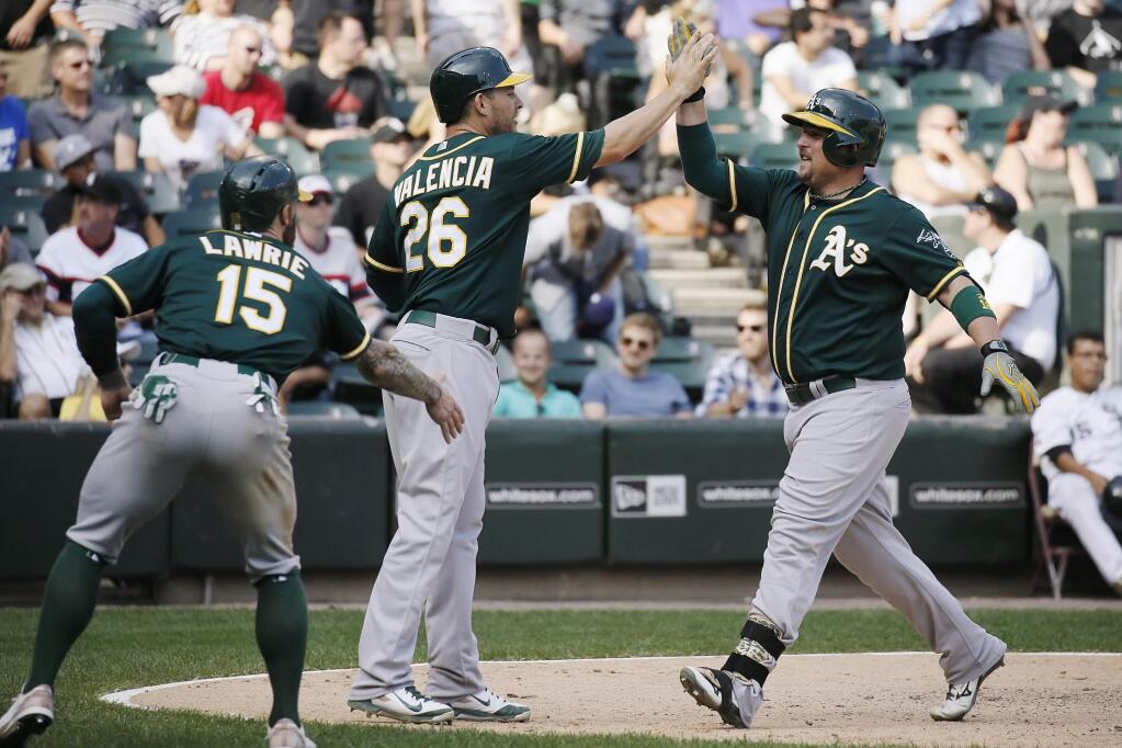 Oakland Athletics designated hitter Billy Butler, right, celebrates with Danny Valencia (26) and Brett Lawrie (15), who scored on this three-run home run during the ninth inning of a baseball game against the Chicago White Sox Thursday, Sept. 17, 2015, in Chicago. (AP Photo/Andrew A. Nelles)