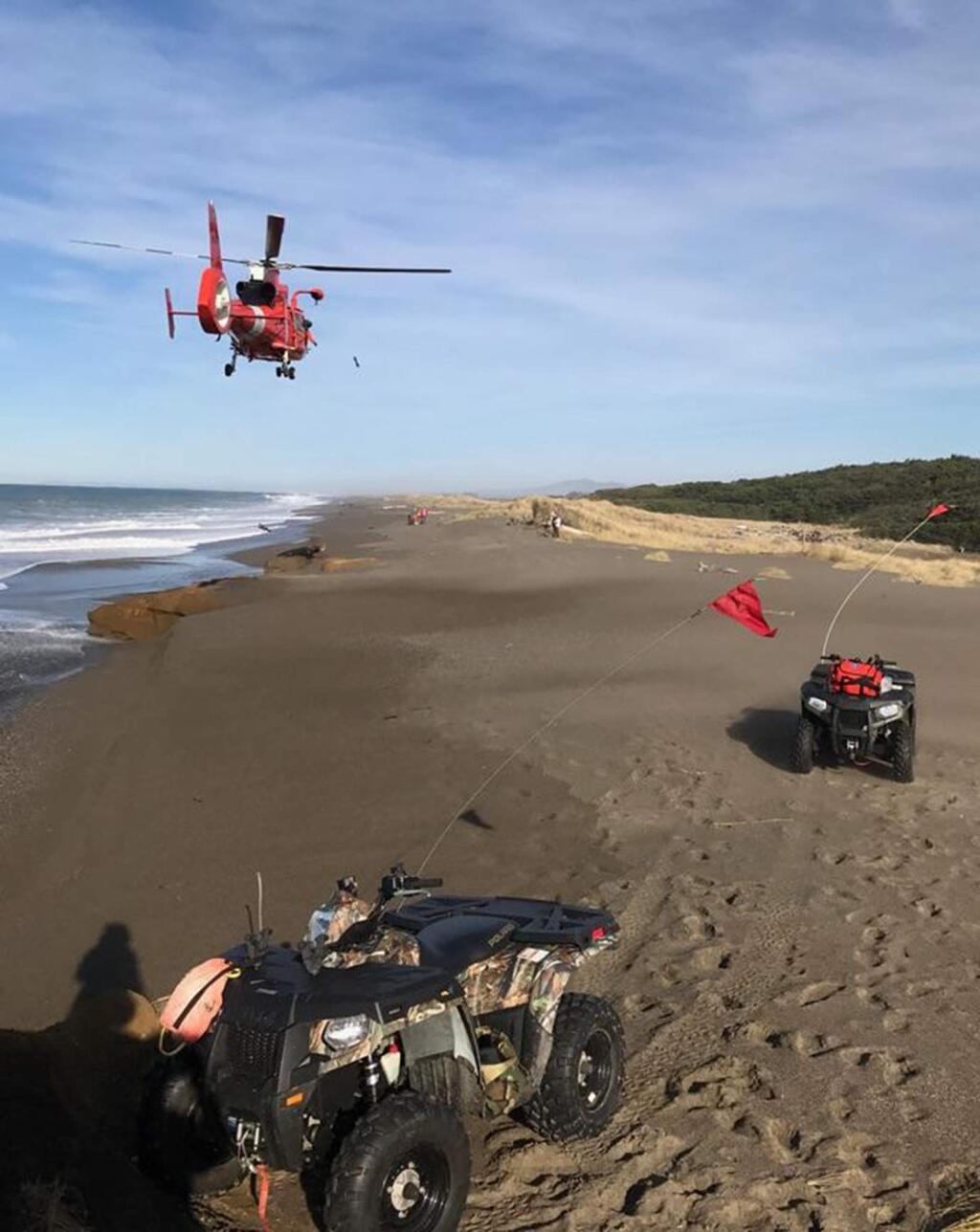 In this photo provided by the Oregon State Police taken Sunday, Jan. 15, 2017, a U.S. Coast Guard helicopter searches a beach about two miles north of Cape Blanco, Oregon, where a father and his young son were swept out to sea Sunday as they walked near the surf. (Oregon State Police via AP)