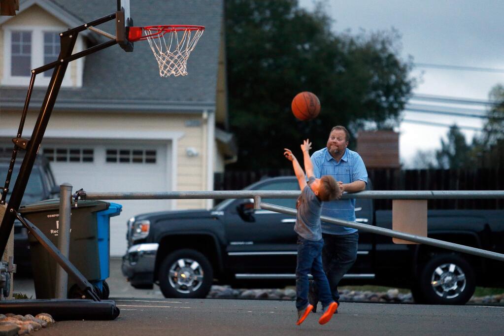 Joshua Nix watches his son Cody, 6, shoot hoops after dinner, at their new home in Santa Rosa, California, on Wednesday, March 21, 2018. The Nix Family experienced an insurance shortfall when they tried to rebuild their home in the Larkfield neighborhood burned down in the Tubbs fire. (Alvin Jornada / The Press Democrat)