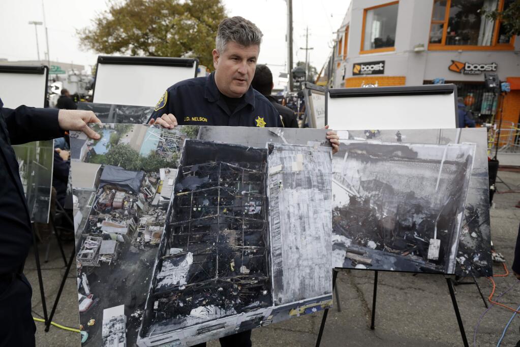 Alameda County Sheriff J.D. Nelson holds an aerial picture of a warehouse fire near the site Monday, Dec. 5, 2016, in Oakland, Calif. The death toll in the fire climbed Monday with more bodies still feared buried in the blackened ruins, and families anxiously awaited word of their missing loved ones. (AP Photo/Marcio Jose Sanchez)