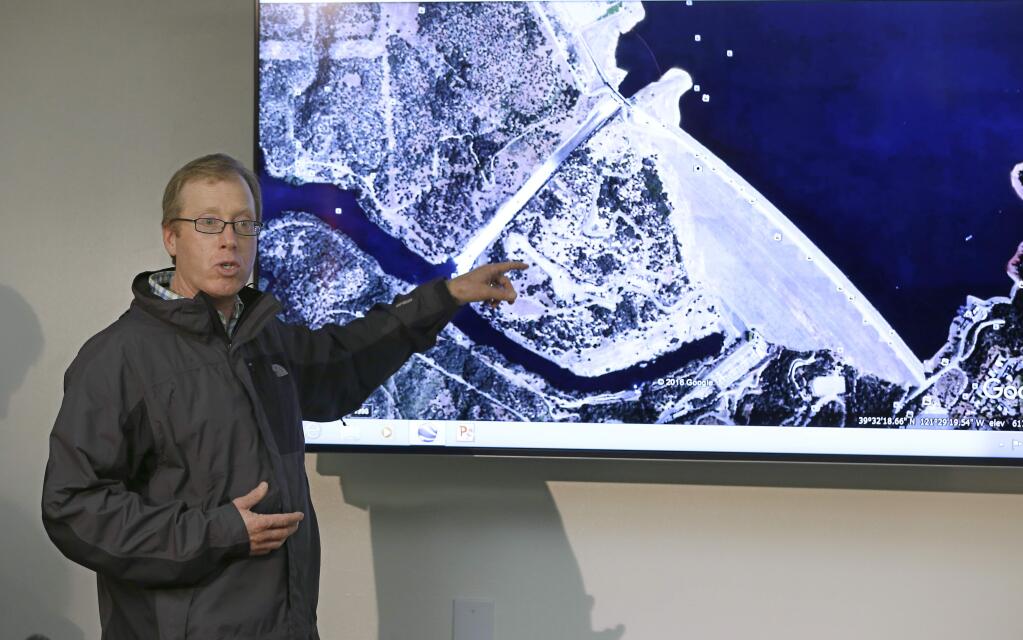 Eric See, of the California Department of Water Resources, gestures to an aerial photo of the Oroville Dam spillway during a news conference, Thursday, Feb. 9, 2017, in Oroville, Calif. Earlier this week, chunks of concrete went flying off the spillway, creating a 200-foot-long, 30-foot deep hole. (AP Photo/Rich Pedroncelli)