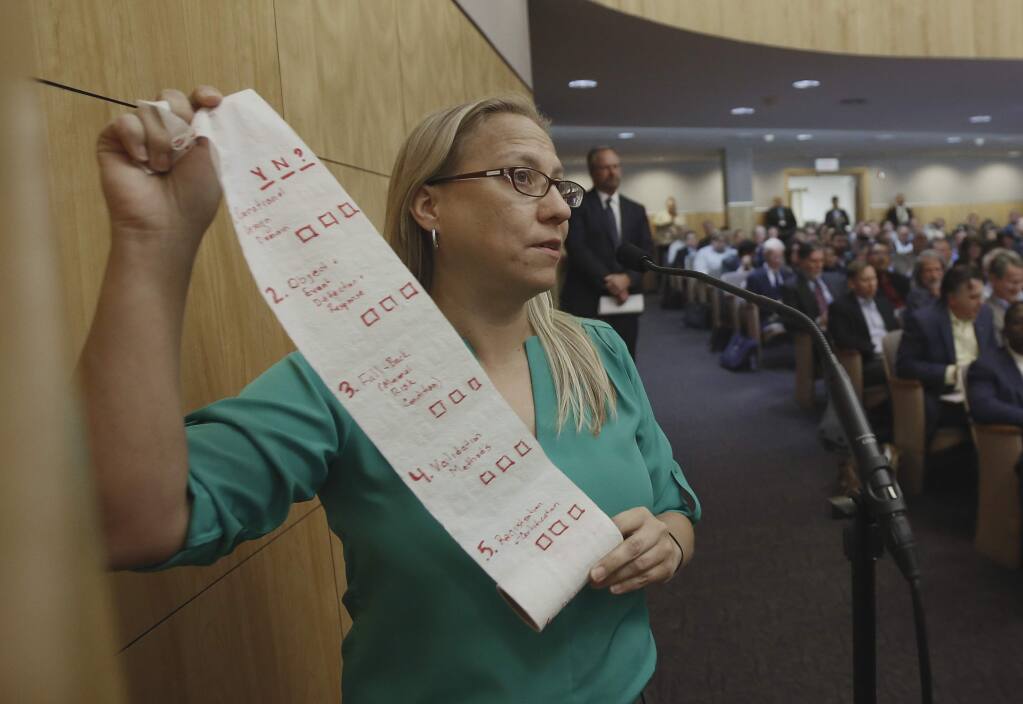 Carmen Balber, executive director of Consumer Watchdog, displays a roll of toilet paper as a prop to say the proposed regulations for self-driving cars are paper thin, during a hearing at the Capitol in Sacramento, Calif., Wednesday, Oct. 19, 2016. The California Department of Motor Vehicles held a workshop Wednesday to let the public comment on proposed regulations that would, eventually, permit self-driving cars that lack a steering wheel or pedals on public roads. (AP Photo/Rich Pedroncelli)