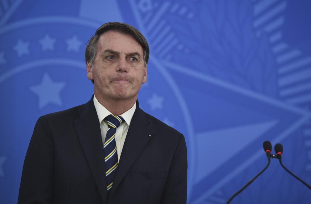 Brazil's President Jair Bolsonaro speaks to journalists about the new coronavirus at Planalto presidential palace in Brasilia, Brazil, Friday, March 27, 2020. Even as coronavirus cases mount in Latin America's largest nation, Bolsonaro is calling the pandemic a momentary, minor problem and saying strong measures to contain it are unnecessary. (AP Photo/Andre Borges)