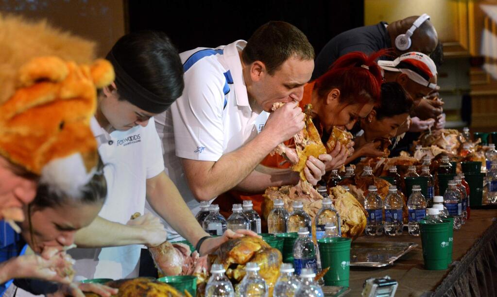 In this Nov. 22, 2014 photo, Joey Chestnut, center, and the other eaters participate in the World Turkey-Eating Championship at Foxwoods Resort and Casino in Mashantucket, Conn. Chestnut won the contest in Connecticut, setting a record by devouring an entire bird. (AP Photo/The Day, Dana Jensen)