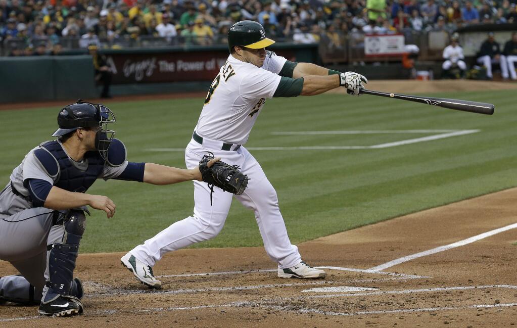 Oakland Athletics' Josh Phegley, right, hits a two-run double in front of Seattle Mariners catcher Mike Zunino during the first inning of a baseball game in Oakland, Calif., Thursday, July 2, 2015. (AP Photo/Jeff Chiu)