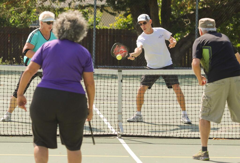 Pat Crabtree attempts to return the ball over the net to Patricia Souza and Jim Johnson while his team mate Bernice Fowler looks on during their pickleball game at Lucchesi park on Tuesday, June 8, 2015. (SCOTT MANCHESTER/ARGUS-COURIER STAFF)