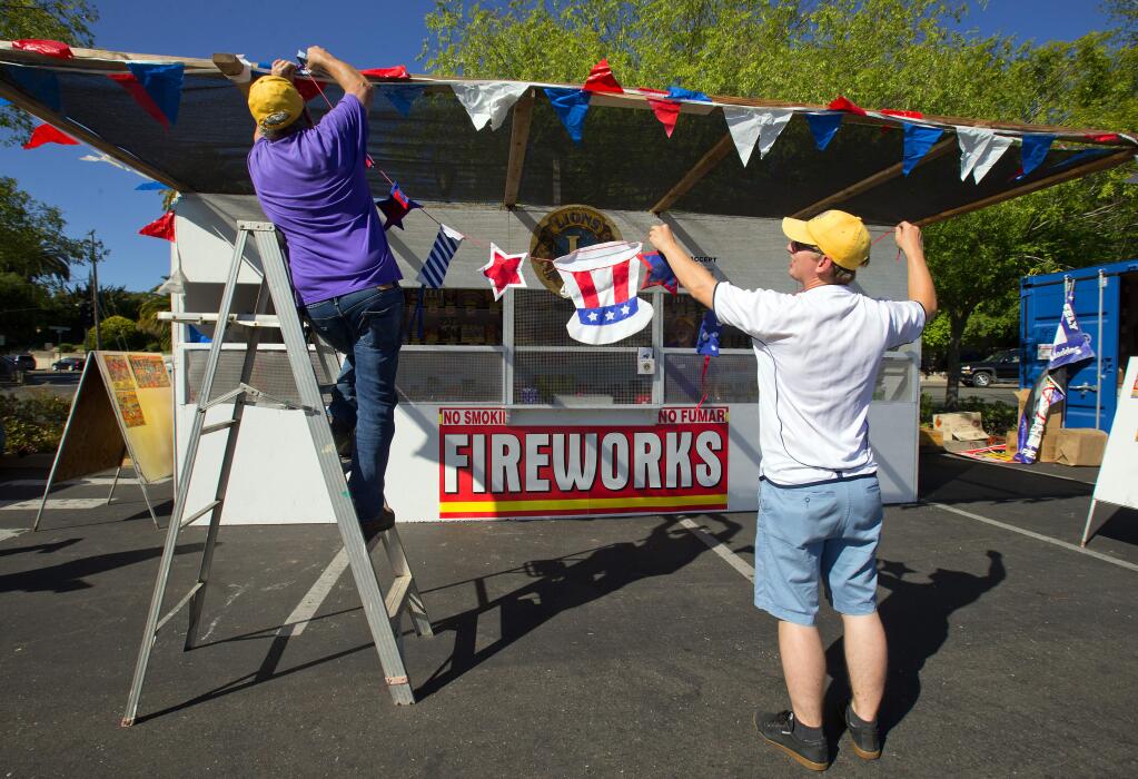 Don Canardo and Mike Stanford hang Fourth of July banners on the Sebastopol Lions Club fireworks booth. (JOHN BURGESS/ PD FILE)