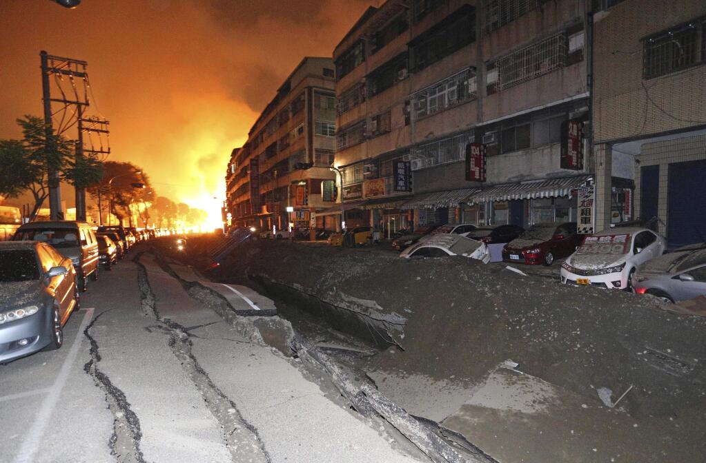 Tossed vehicles line an destroyed street as flames continue to burn from multiple explosions from an underground gas leak in Kaohsiung, Taiwan, early Friday, Aug. 1, 2014. (AP Photo)
