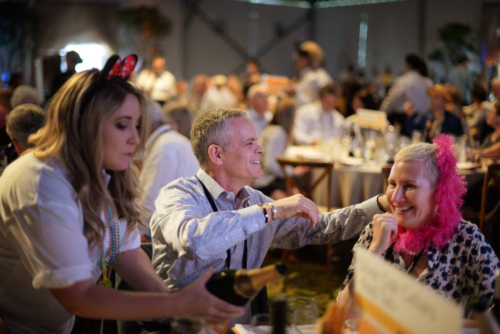 Lisa Hogle, left, pouring sparkling wine after David Duncan, center, and Kary Duncan of Silver Oak Cellars celebrate after their winning bid on the Martinelli Winery and Ramey Wine Cellars live auction Lot #2 at the Sonoma County Wine Auction held at La Crema Estate at Saralee's Vineyard in Windsor, California on Saturday. September 16, 2017.(Photo: Erik Castro/for The Press Democrat)