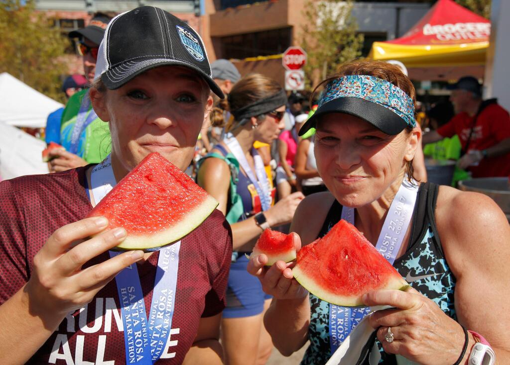 Santa Rosans Carolyn Collins, left, and her mother, Cheryl Collins, enjoy slices of watermelon after they both completed the Santa Rosa Half Marathon in Santa Rosa, California on Sunday, Aug. 27, 2017. (ALVIN JORNADA/ PD FILE)