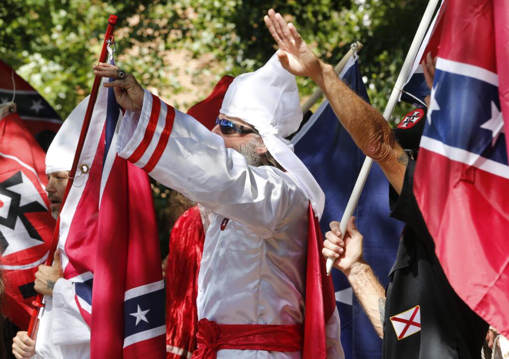 Ku Klux Klan members salute during a July 8 rally in Charlottesville, Virginia -- five weeks prior to a right-wing demonstration that ended in a violent clash with counter-demonstrators. (STEVE HELBER / Associated Press)
