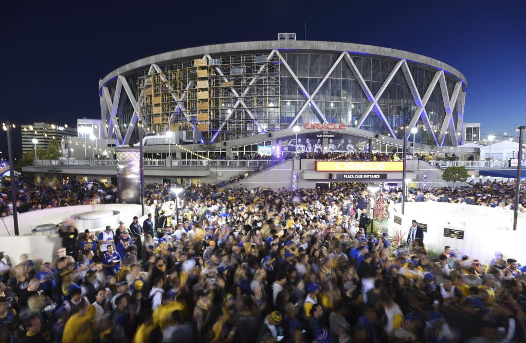 In this June 8, 2018, file photo, Golden State Warriors fans celebrate outside Oracle Arena in Oakland after the Warriors won the NBA championship. The Warriors are playing their final season at the arena and will be moving to Chase Center in San Francisco in 2019. (AP Photo/Josh Edelson, File)