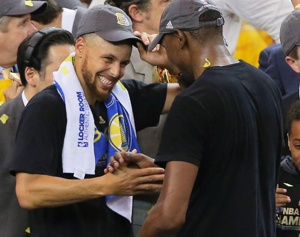 Golden State Warriors guard Stephen Curry and forward Kevin Durant celebrate on stage after Game 5 of the NBA Finals in Oakland on Monday, June 12, 2017. The Warriors won the NBA championship by defeating the Cavaliers 129-120. (Christopher Chung / The Press Democrat)