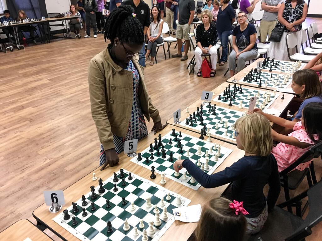 A young chess student makes her move against Phiona Mutesi, the queen of Katwe and internationally recognized chess player, at a Chess for Kids event in Rohnert Park on Saturday, Aug. 12, 2017. ( NICK RAHAM / PRESS DEMOCRAT)