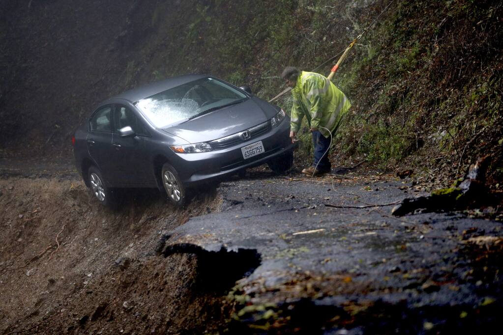 John Yost from Occidental Towing works to remove a car following a mudslide that occurred Tuesday morning near the top of Old Cazadero Road in Guerneville, on Wednesday, Feb. 8, 2017. (BETH SCHLANKER/ The Press Democrat)