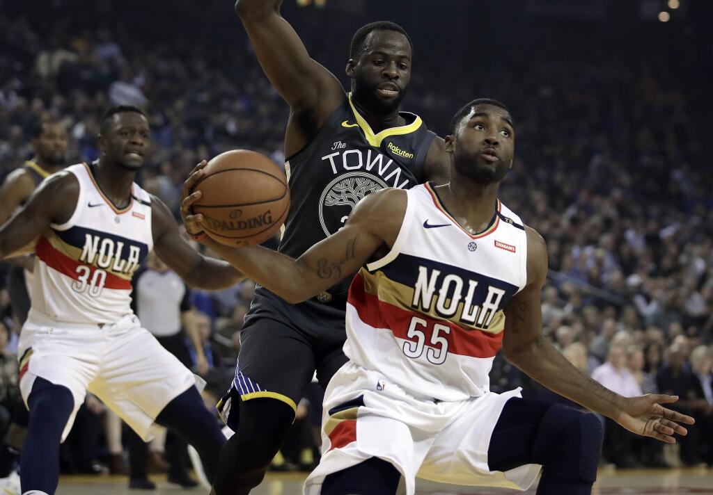 The New Orleans Pelicans' E'Twaun Moore (55) looks to pass the ball away from the Golden State Warriors' Draymond Green during the first half Wednesday, Jan. 16, 2019, in Oakland. (AP Photo/Ben Margot)