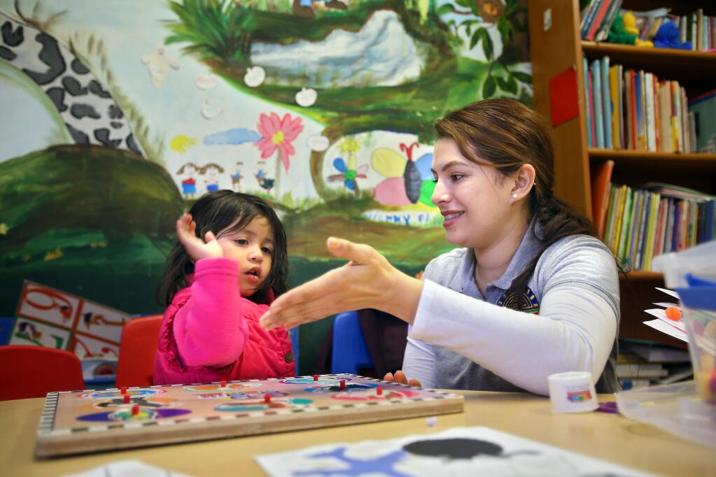 Childcare provider Enedina Reyes gets a high-five from two-year-old Sarahy Argota after completing a puzzle at La Luz, in Sonoma on Tuesday, January 20, 2015. (Christopher Chung/ The Press Democrat)