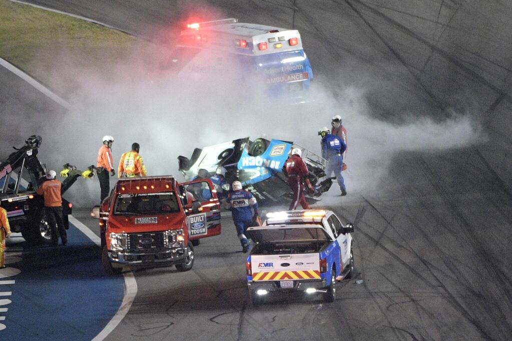 Track personnel arrive to help Ryan Newman (6) after he flipped his car on the final lap in front of the grandstands during the NASCAR Daytona 500 auto race at Daytona International Speedway, Monday, Feb. 17, 2020, in Daytona Beach, Fla. (AP Photo/Phelan M. Ebenhack)