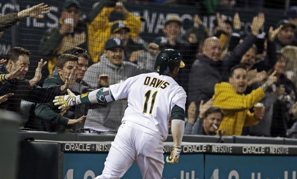 In this April 4, 2017, file photo, Oakland Athletics' Rajai Davis celebrates with fans as he scores on a throwing error after hitting a two-run triple off Los Angeles Angels' Bud Norris during the seventh inning in Oakland. The Athletics will expand protective netting between the stands and the playing field to the far ends of both dugouts ahead of the 2018 season.(AP Photo/Ben Margot, File)