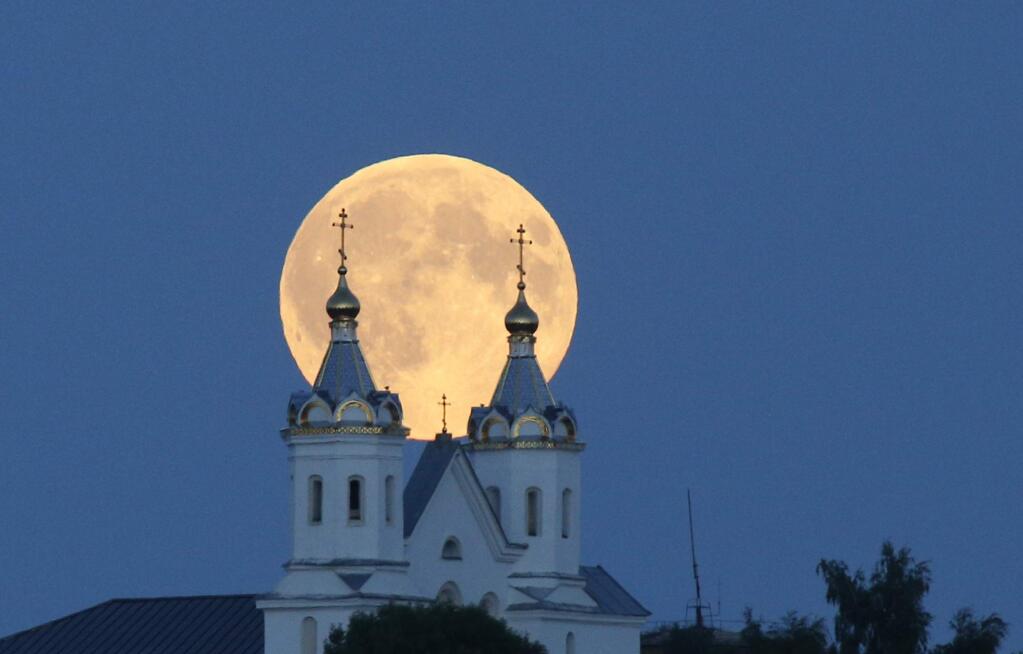 A perigee moon, also known as a super moon, rises above the Orthodox Church in the town of Novogrudok, 150 kilometers (93 miles) west of the capital Minsk, Belarus, Saturday, Aug. 29, 2015. The supermoon happens when moon is full and makes it closest approach to Earth in her orbit. (AP Photo/Sergei Grits)