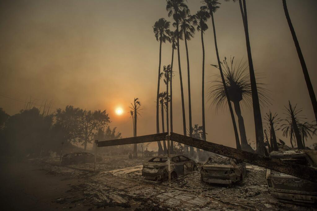 FILE - In this Dec. 5, 2017, file photo, Smoke rises behind a leveled apartment complex as a wildfire burns in Ventura, Calif. Over 100 structures have burned so far in Ventura County, officials said. President Donald Trump has declared a major disaster in California over a wildfire that destroyed more than 1,000 buildings. The White House announced Tuesday, Jan. 2, 2018, that the president has granted disaster status, which will help make federal funds available to supplement recovery efforts in the wake of the Thomas Fire that ravaged Santa Barbara and Ventura counties. (AP Photo/Noah Berger, File)