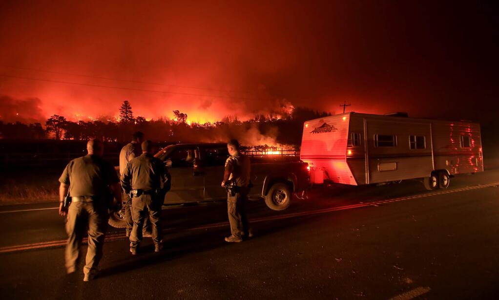 Lake County Sheriff's deputies man a road block as the Valley fire rages in the background in Middletown, Sunday morning Sept. 13, 2015. (Kent Porter / Press Democrat) 2015