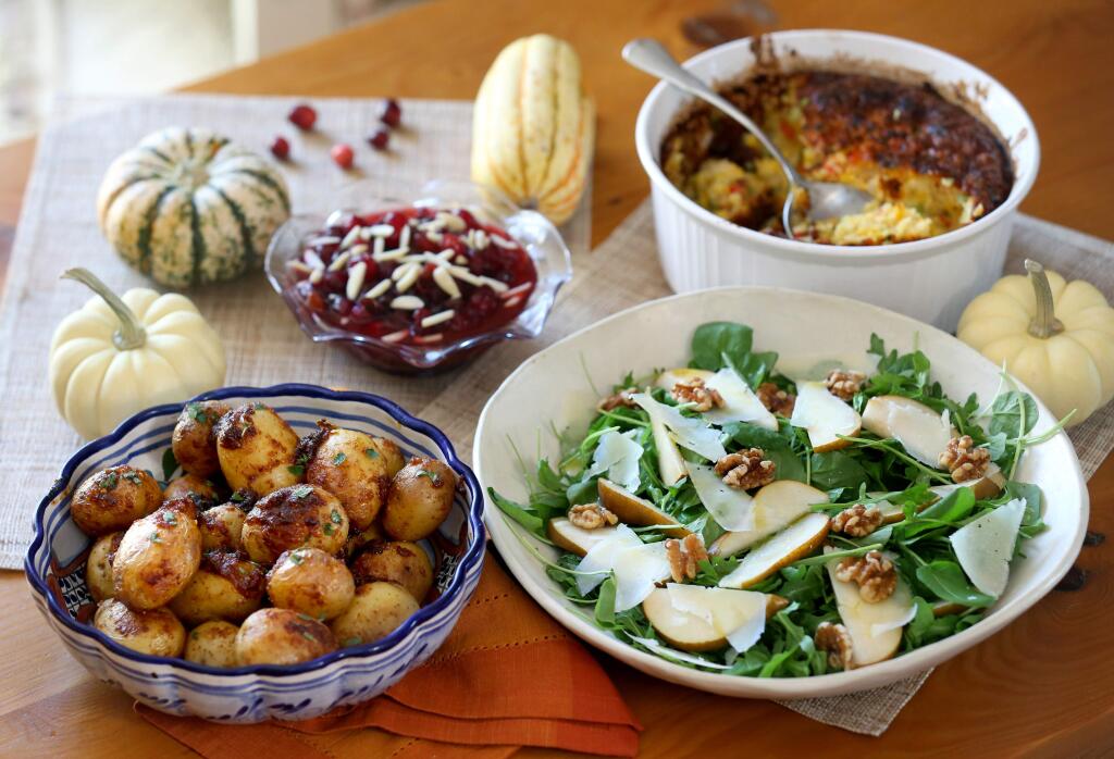 Papas a la diabla, cranberry sauce with raisins and slivered almonds, corn pudding, and salad with pears, cheese and walnuts. Photo taken in Santa Rosa on Wednesday, Nov. 20, 2019. (BETH SCHLANKER/ The Press Democrat)